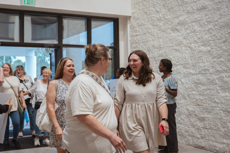 Two friends greeting each other with warm smiles at the Abide conference.